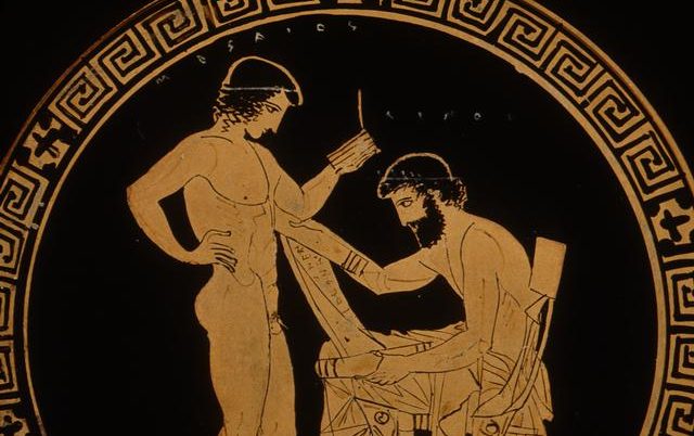 Ancient plate with Greek Key design around rim. Depiction of a young naked man standing next to a seated beareded man reading a scroll.