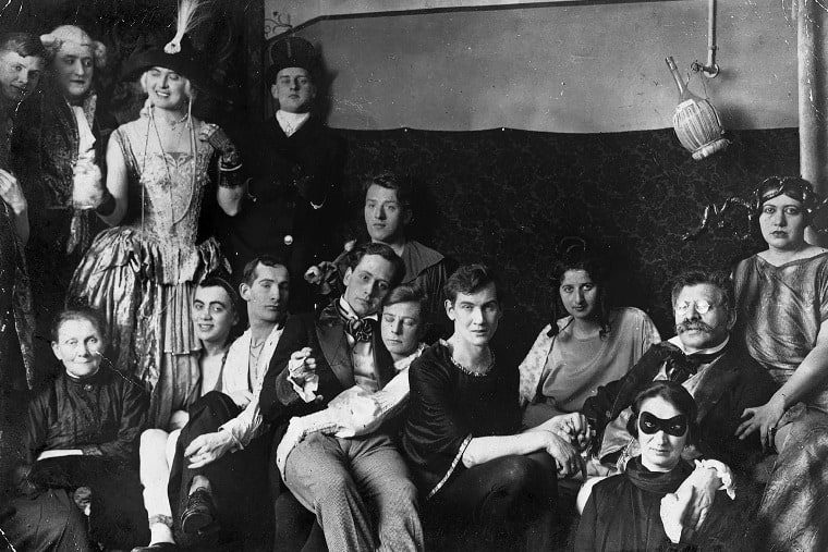Photograph featuring people in a bar setting, with many dressed in clothing typically not associated with their gender.
